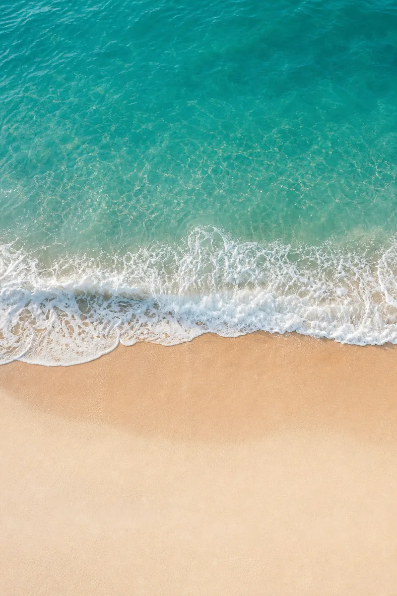 Teal wave curling onto pale sand