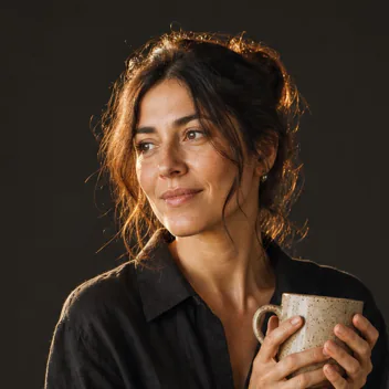 Woman with dark hair holding a handmade ceramic mug