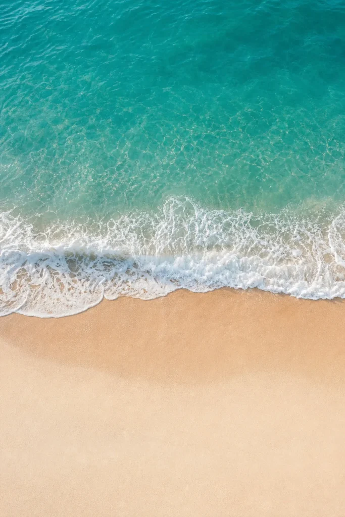Teal wave curling onto pale sand